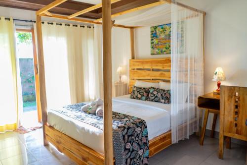 AirsatangWest Break Bali - Medewi的一间卧室配有一张天蓬床和一张书桌