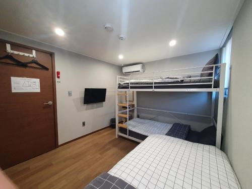 首尔Hao Guesthouse in Hongdae的小房间设有两张双层床和一扇门