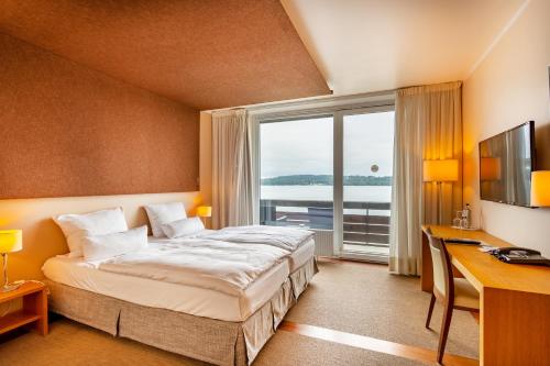 施坦贝尔格湖畔贝格莱尼赛酒店的配有一张床、一张书桌和一扇窗户的酒店客房