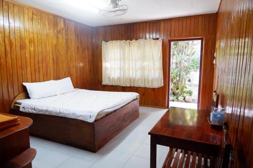 他曲Song Lao Guesthouse的一间卧室配有一张床、一张书桌和一个窗户。