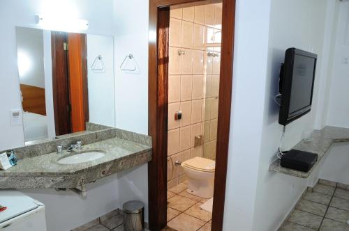 伊帕廷加Panorama Tower Hotel的一间带水槽和卫生间的浴室以及一台电视。