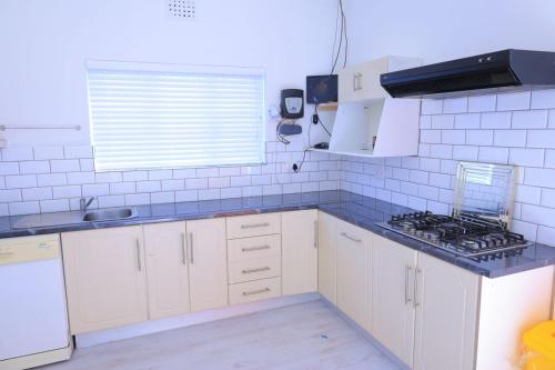 开普敦Lalibela gust house 2的厨房配有白色橱柜和蓝色台面