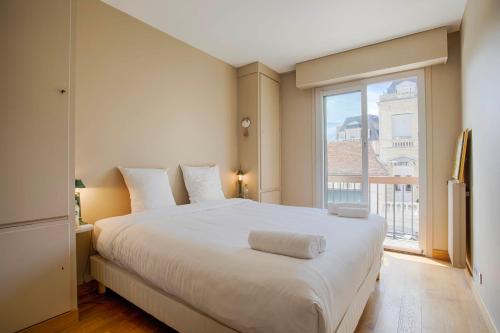 多维尔Les Cigognes - Deux Pièces - Deauville Centre的卧室设有一张白色大床和一扇窗户。