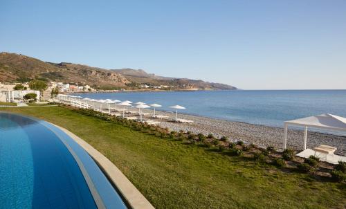 科林瓦里奥Giannoulis - Grand Bay Beach Resort (Exclusive Adults Only)的游泳池旁海滩上的一排遮阳伞