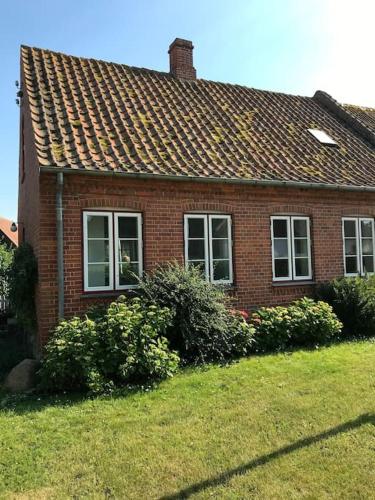 斯泰厄Vidunderligt hus på smukke Nyord的前面有灌木丛的红砖房子