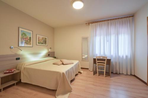 Noventa VicentinaHotel da Romagnolo的一间卧室配有一张床、一张桌子和一个窗户。