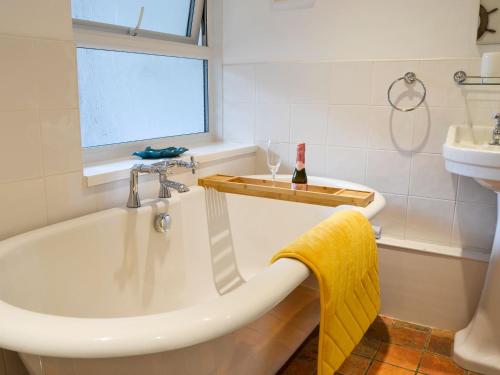 MundfordTree Tops Cottage的带浴缸、水槽和窗户的浴室