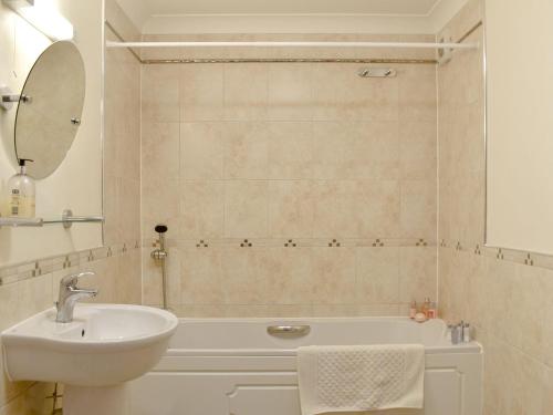 纽基Seaview Apartment - 21 Spinnakers的一间带水槽、浴缸和镜子的浴室