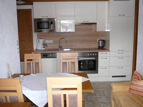 Ehenbichl凯瑟琳度假屋的一间厨房,内设白色橱柜和一张桌子