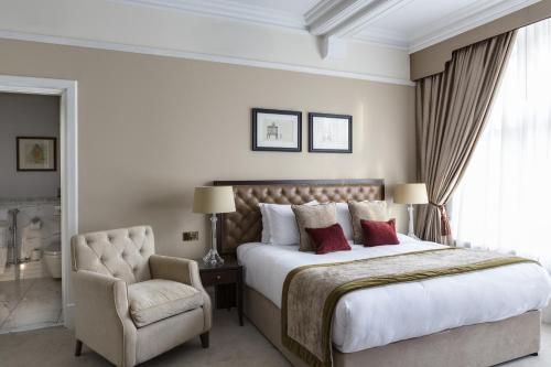 伦敦圣保罗酒店的一间卧室配有一张大床和一把椅子