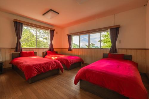 轻井泽Kanra-gun - House / Vacation STAY 2833的宿舍间的两张床,配有红色床单和窗户