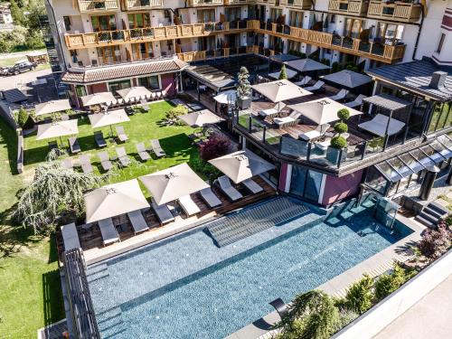 科姆梅扎杜拉Tevini Dolomites Charming Hotel的享有酒店空中美景,设有游泳池和桌椅