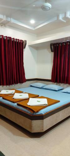 舍地Sai Raghunandan Guest House的红色窗帘的房间的一张床位