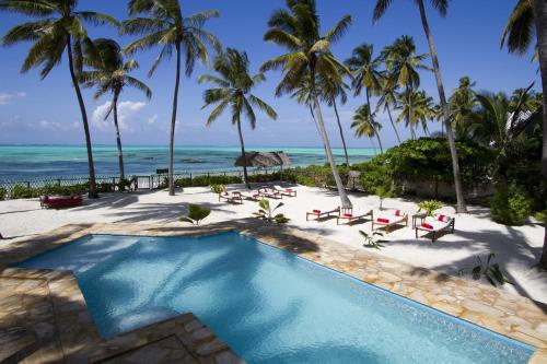 江比阿Raha Lodge Zanzibar Boutique Hotel的棕榈树和海洋海滩上的游泳池