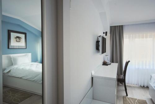 普里什蒂纳Hotel Callisto的一间卧室配有一张床、一张书桌和一面镜子