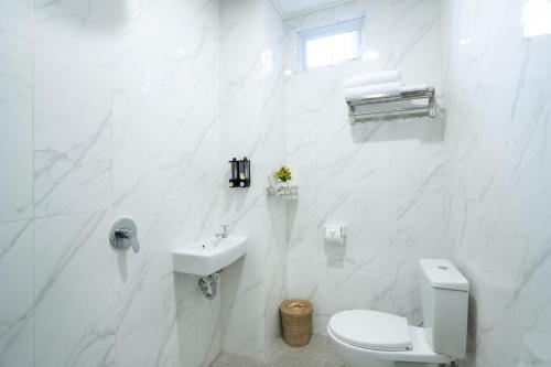 库塔Oki Taru Residence的白色的浴室设有卫生间和水槽。
