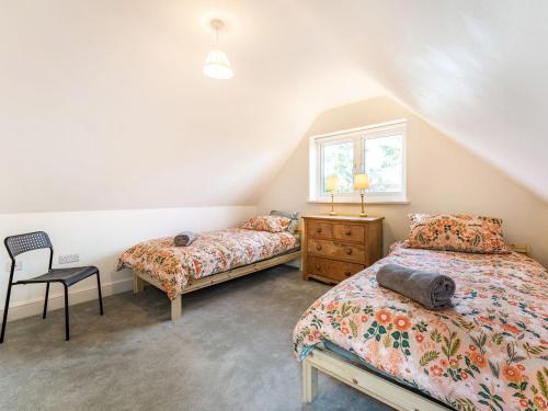 巴特尔Caldbec House Stables的一间卧室设有两张床、一把椅子和一个窗户。