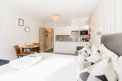 莱瑟姆-圣安妮Prime Suites Lytham的一间带白色大床的卧室和一间厨房