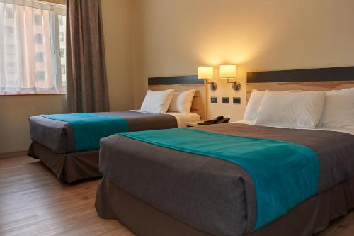 塔尔卡Hotel Diego de Almagro Talca Express的酒店客房设有两张床和窗户。