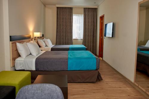 塔尔卡Hotel Diego de Almagro Talca Express的酒店客房设有两张床和电视。