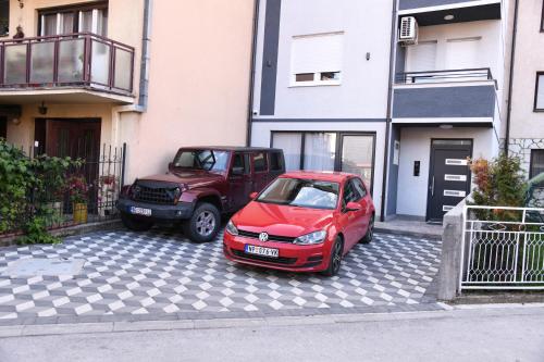 新帕扎尔Demir Apartmani的两辆汽车停在大楼旁边的停车场