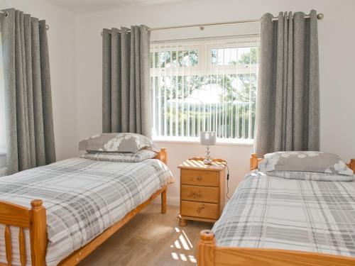 Drumshanbo-GlebeMaple Cottage的一间卧室设有两张单人床和一个窗户。