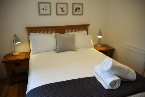 皮特洛赫里The Gardeners Cottage的一间卧室配有一张带毛巾和两盏灯的床。