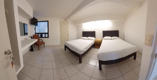 阿瓜斯卡连特斯Hotel el Cortes的客房设有两张床和水槽。