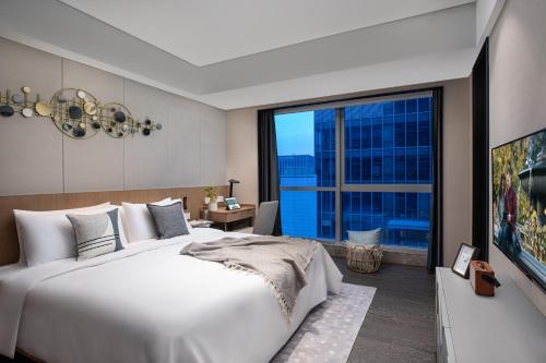 无锡无锡馨乐庭新发公寓酒店的卧室设有一张白色大床和大窗户