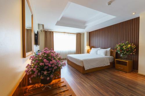 胡志明市罗斯兰科普酒店的一间酒店客房,在房间内摆放着床和鲜花