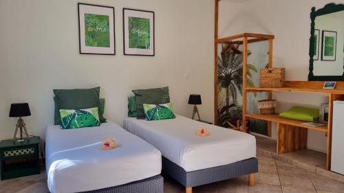 珀蒂蒂勒Maison d'hôtes Villa des Mascareignes的配有白色床单和绿色枕头的客房内的两张床