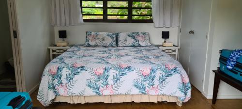 拉罗汤加Eve and Sandys Holiday Home的一间卧室配有一张带花卉床罩的床和窗户。