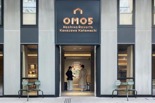 金泽OMO5 Kanazawa Katamachi by Hoshino Resorts的两个人站在商店门口