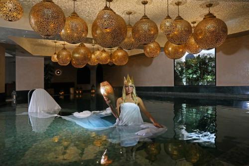 马拉喀什Hotel Jadali & Spa的坐在游泳池里的穿着衣服的女人