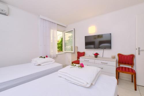 木洛希尼Apartments Antares的一间白色卧室,配有两张床和电视