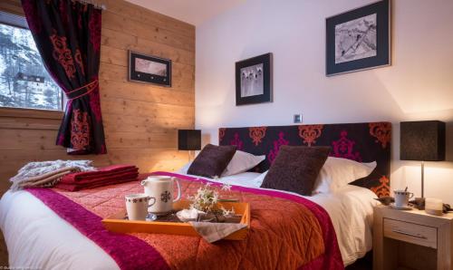 蒂涅CGH Résidence Boutique Le Lodge des Neiges的一间卧室配有两张红色和白色床单