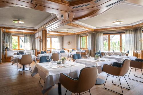 腓特烈港Hotel Maier的餐厅设有白色的桌椅和窗户。