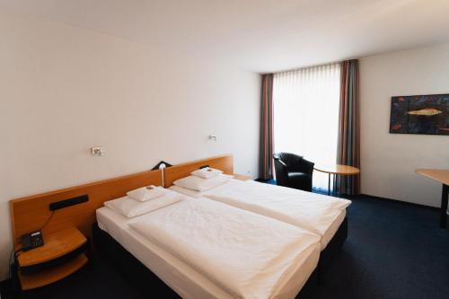 埃尔克伦茨Hotel am Weiher的酒店客房设有一张白色大床和一张书桌
