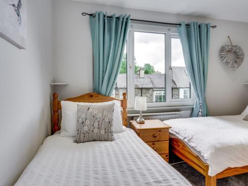 鲍内斯温德米尔Gorgeous cottage in Bowness的一间卧室设有两张床和窗户。