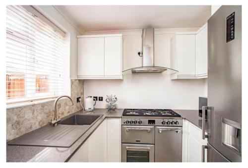 利夫斯登格林2 Bed - walking distance to Harry Potter Studio的厨房配有白色橱柜和炉灶烤箱。