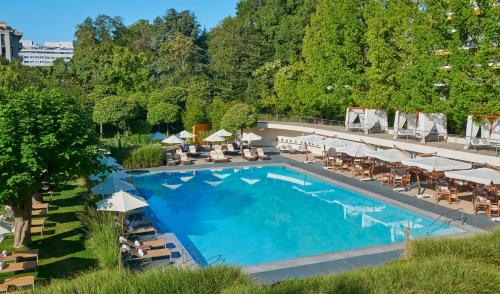 日内瓦InterContinental Genève, an IHG Hotel的享有带椅子和遮阳伞的游泳池的上方景色