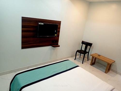 古瓦哈提VIAN INN的配有床、电视和椅子的房间