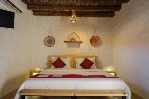 Shāhiq萨玛瓦希尔沙漠露营地的一间卧室配有一张带红色和白色枕头的大床