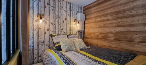 圣热尔韦莱班Elégant et moderne, au pied du Mont-Blanc的一间卧室设有木墙和一张带枕头的床。