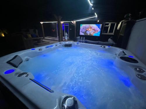 斯凯格内斯Hot tub, 110Inch Outdoor Cinema, Fire Pit, 4 Acre garden, Luxury 5 Star Woodland Lodge的客房内的按摩浴缸配有电视