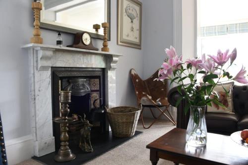 皮特洛赫里Tigh Na Cloich的客厅设有壁炉和带鲜花的桌子。