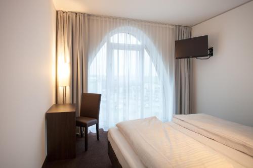 本斯海姆托巴肯酒店的一间卧室配有一张床、一张书桌和一个窗户。
