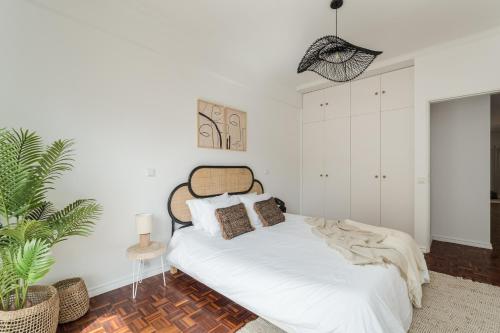 里斯本Casa Boma Lisboa - Design & Spacious Apartment With Balcony - Alvalade II的一间白色卧室,配有床和植物
