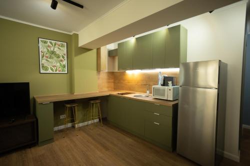 雅西Oliv Residence的厨房配有绿色橱柜和不锈钢冰箱