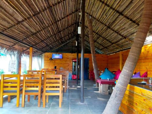 阿贡达Agonda Paradise的餐厅设有木桌、椅子和电视。